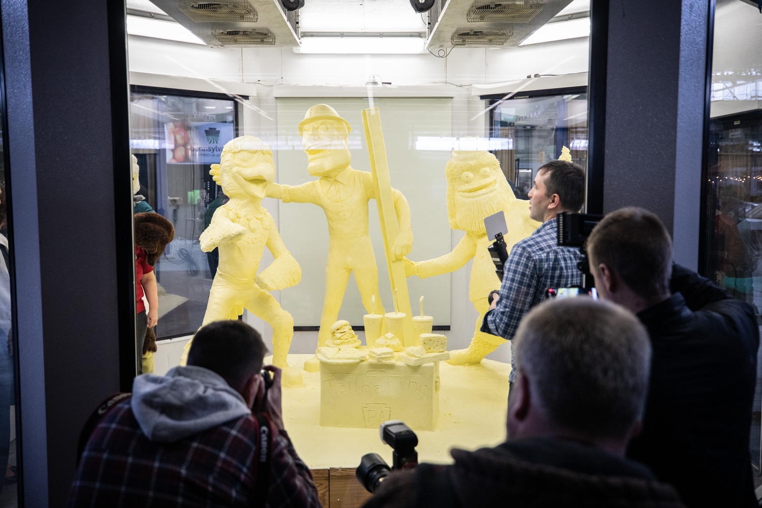 Press crowdind around the butter sculpture for the big reveal. Lt. Governor John Fetterman and Secretary of Agriculture Russell Redding today unveiled the 2020 Pennsylvania Farm Show butter sculpture, carved from a half-ton of butter depicting three of Pennsylvanias beloved professional sports mascots: Philadelphia Flyers Gritty, Philadelphia Eagles Swoop, and Pittsburgh Steelers Steely McBeam celebrating with a spread of Pennsylvania dairy products. The sculpture, a long-time Farm Show staple, encourages Pennsylvanians to be a fan of Pennsylvania dairy and give a cheer to the more than 6,200 dairy farmers in the commonwealth.  Harrisburg, PA  January 2, 2020<br><a href="https://filesource.amperwave.net/commonwealthofpa/photo/17646_agric_butter_sculpture_dz_006.jpg" target="_blank">⇣ Download Photo</a>