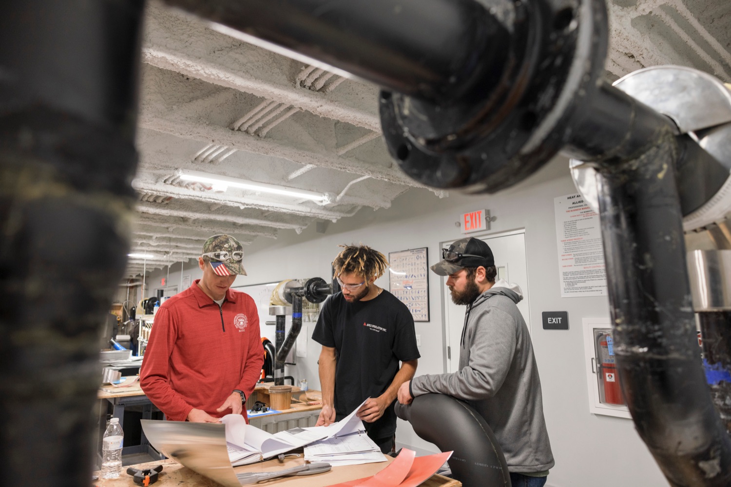 From left; Anthony Ferguson, a part time instructor at Heat and Frost Insulators Local 23; Anthony Riddick, 24, and Josh Schegan, 35, look at layouts for pipe insulation following a press conference which kicked off National Apprenticeship Week with a visit to Heat and Frost Insulators Local 23, a training center in Dauphin County, on Monday, November 14, 2022. National Apprenticeship Week (NAW) is a nationwide celebration for industry, labor, equity, workforce, education and government leaders to showcase the successes and value of registered apprenticeship for building our economy, advancing racial and gender equity, and supporting underserved communities.<br><a href="https://filesource.amperwave.net/commonwealthofpa/photo/22344_li_apprenticeshipweek_NK_010.JPG" target="_blank">⇣ Download Photo</a>